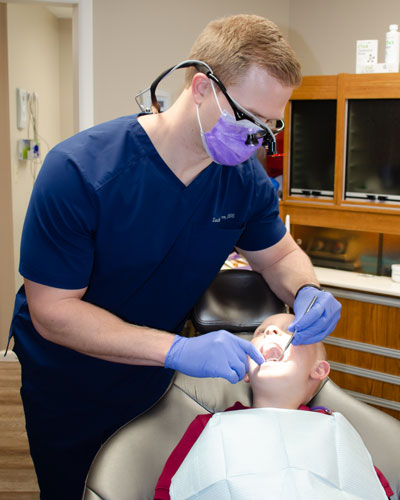 Pediatric dentist inspects a young patient's mouth for cavities